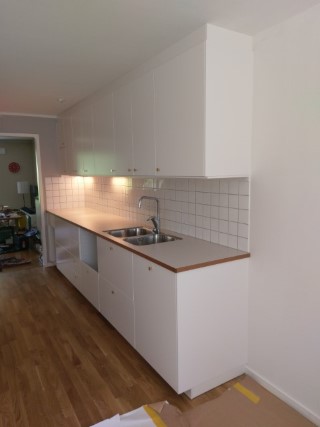 Nyrenoverat kök med vita luckor och virrvarr-bänkskivor